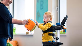 child standing in a Leckey Squiggles standing frame